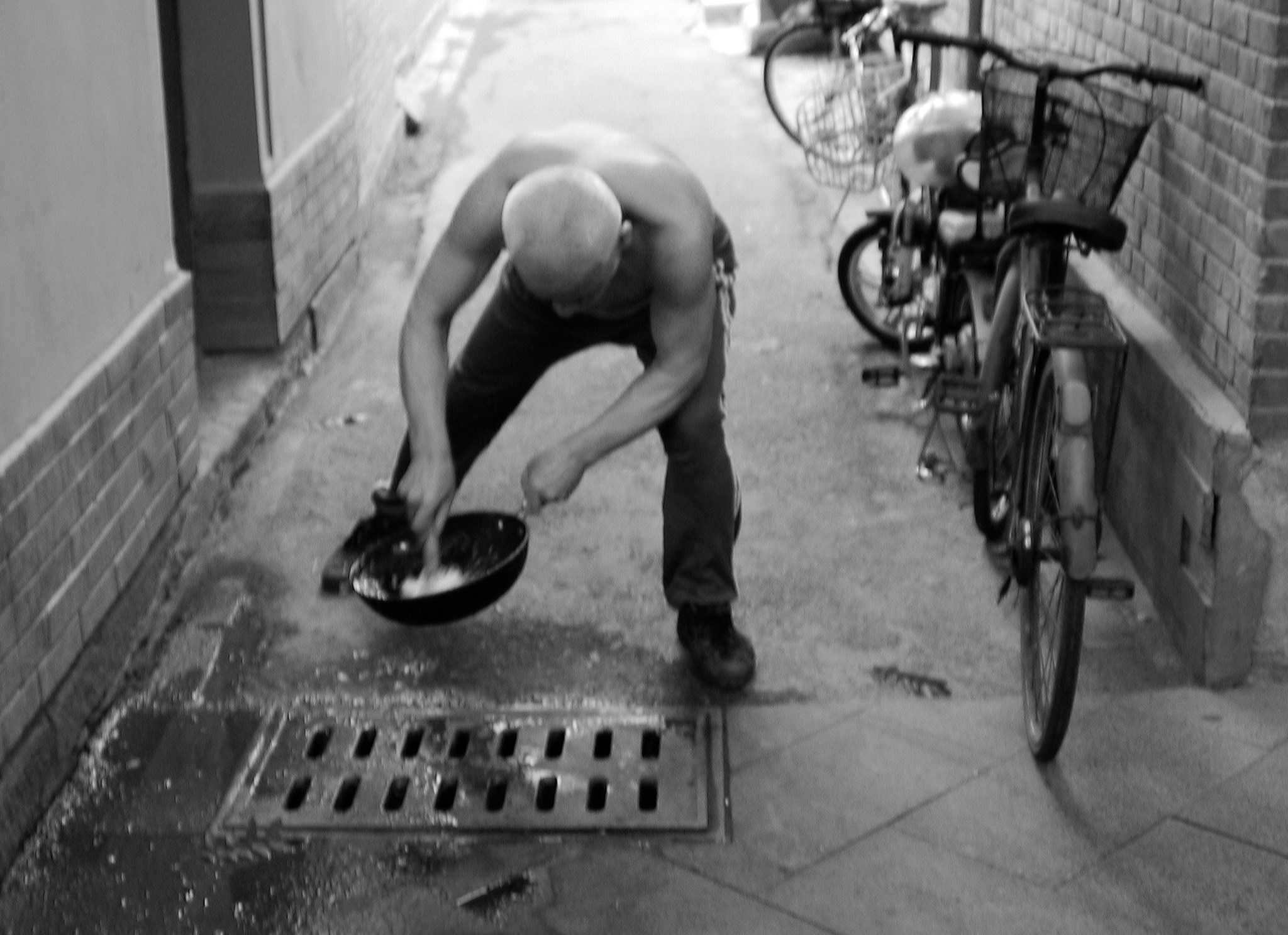 old chinese person cleaning a pan